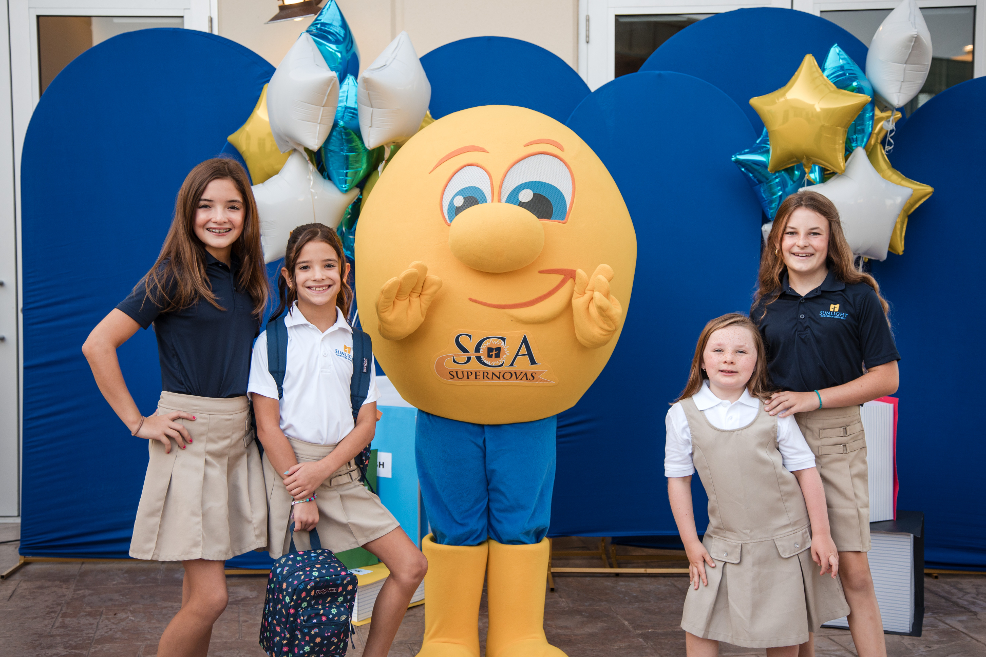 Lower elementary students posing with the SCA Supernovas mascot